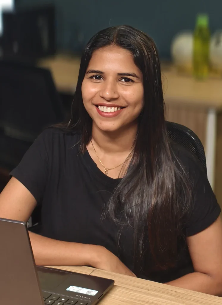 An image of the best freelance digital marketer in Thrissur sitting on a chair in front of a laptop, smiling and looking at the camera.